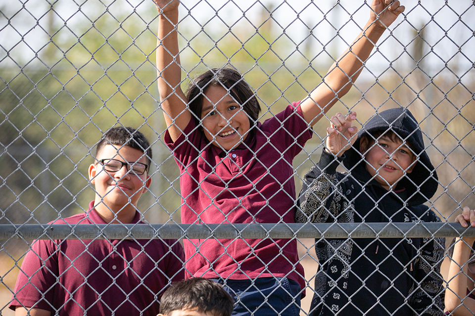 Three students hang out behind the fence
