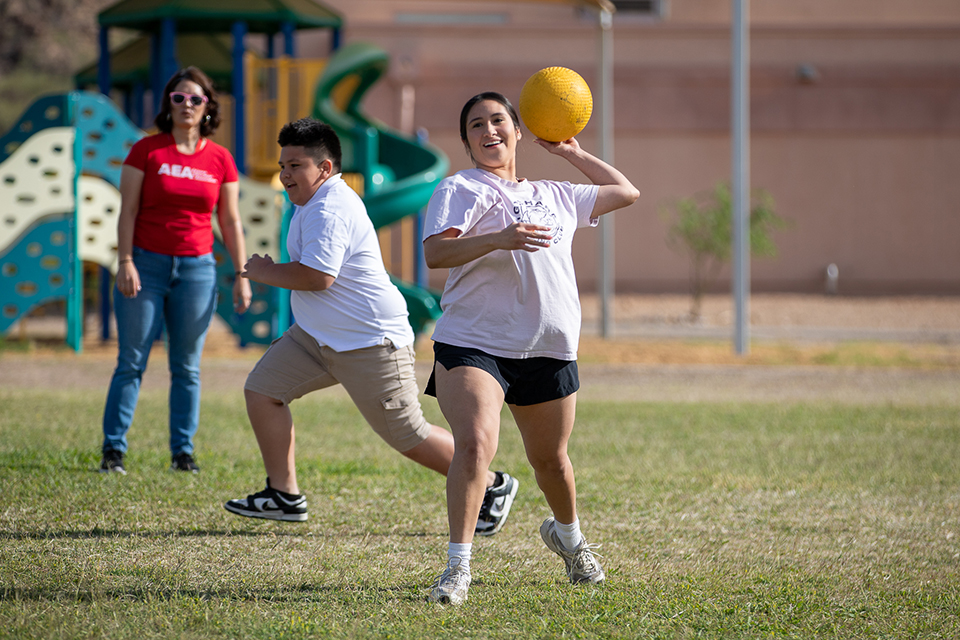 A teacher throws out a yellow kickball