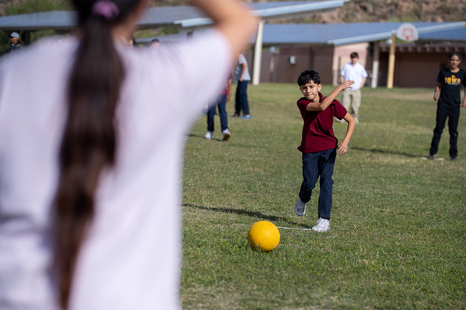 A boy kicks a yellow ball