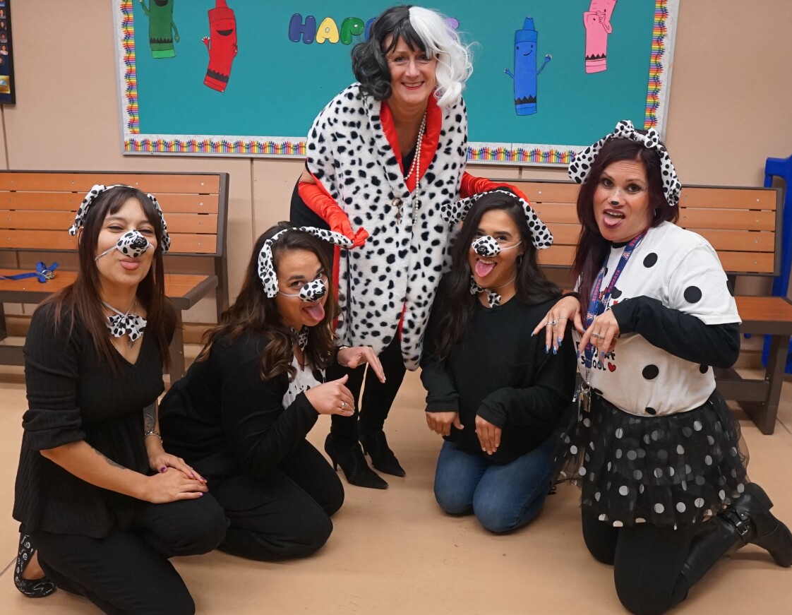 "Cruella de Vil" poses with her staff of Dalmatians!