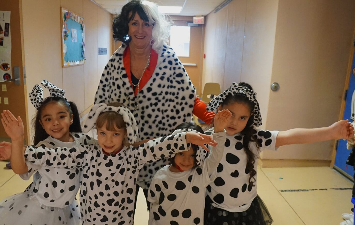 "Cruella de Vil" poses with students dressed as Dalmatian puppies