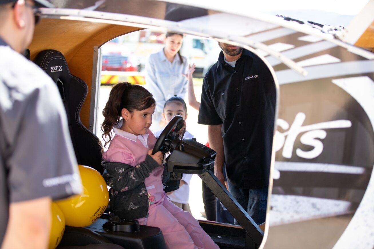 A young girl sits behind the wheel of a large truck on Career Day
